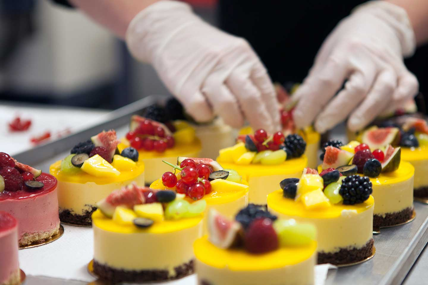 Patisserie-Törtchen werden in der Backstube mit frischen Früchten verziert