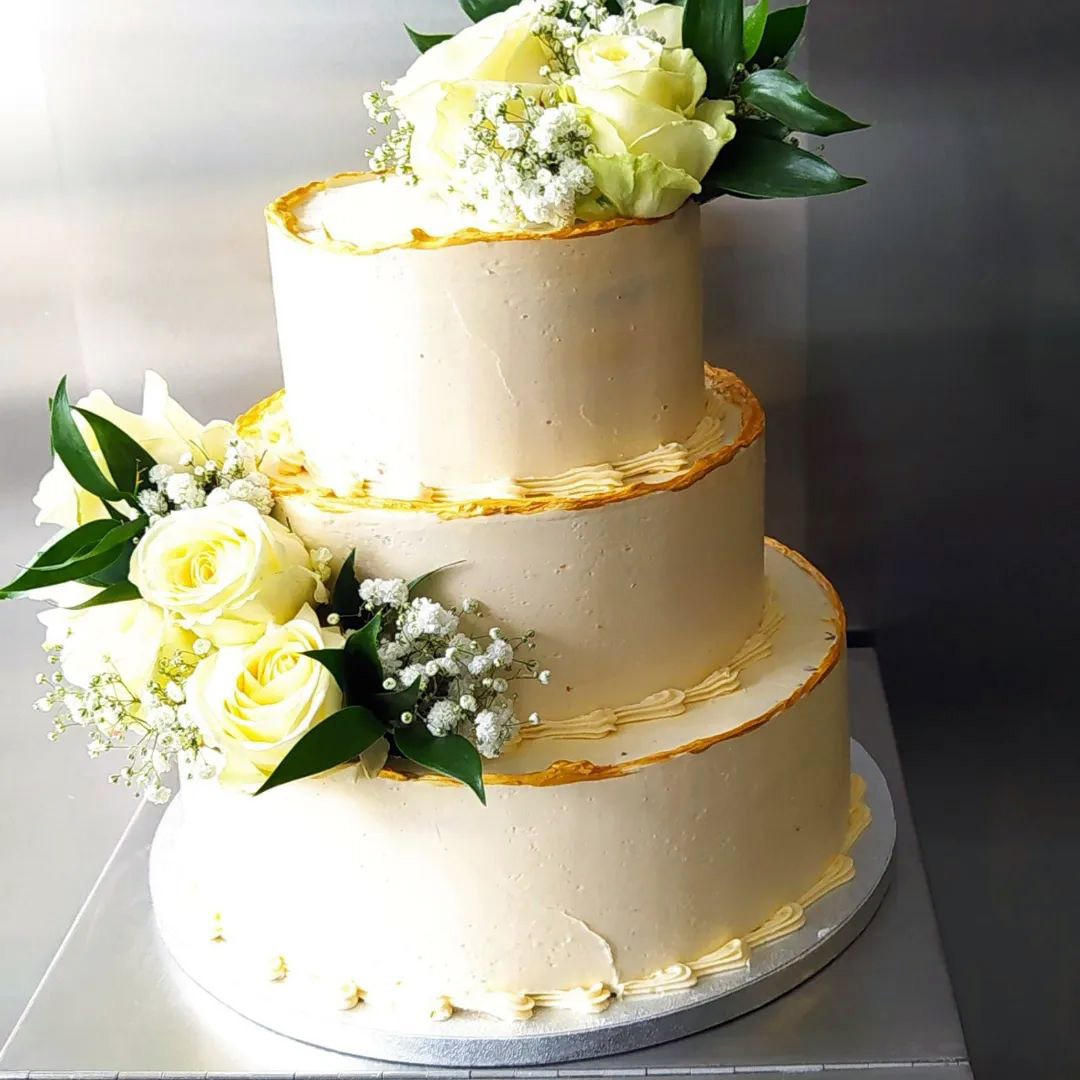 Buttercremetorte mit Goldkanten und weißen Rosen