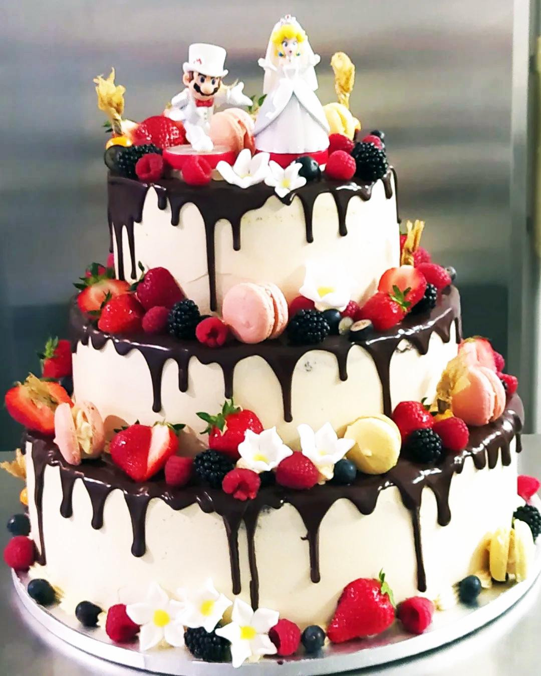 Drip Cake mit Beeren, Macarons und Tortenfiguren